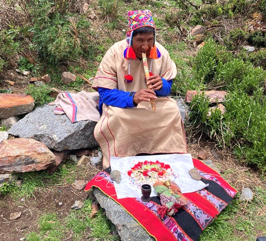 An Andean priest plays the flute over a spread of offerings in a Peruvian Pachamama ceremony