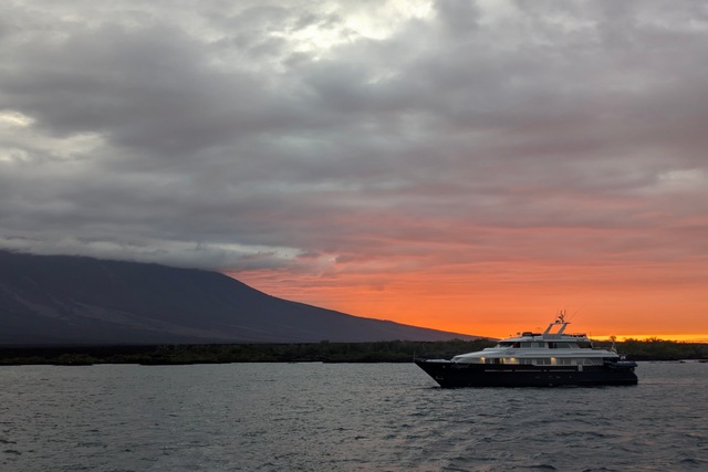 A small Galapgos yacht cruises near Fernandina Island at sunset
