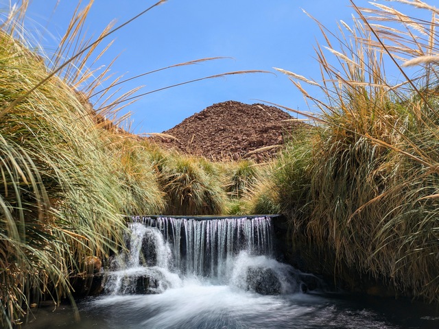 a small waterfall framed by lush grasses in a private pool at Puritama Hot Springs in Chile