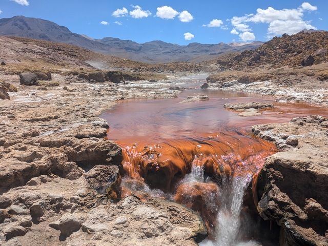 A small waterfall in a red, rocky creek at El Tatio Geyser