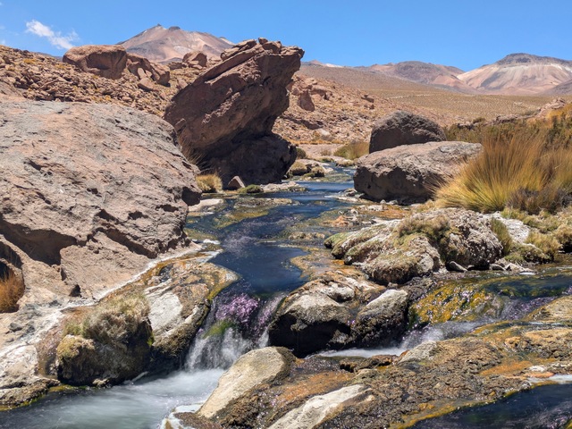 a colorful rocky creek surrounded by rocks, volcanos, and steppe at el tatio geyser