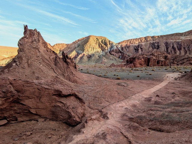 A hiking trail in the Rainbow Valley of the Atacama, with colorful rock formations in hues of red, orange, gold, and green