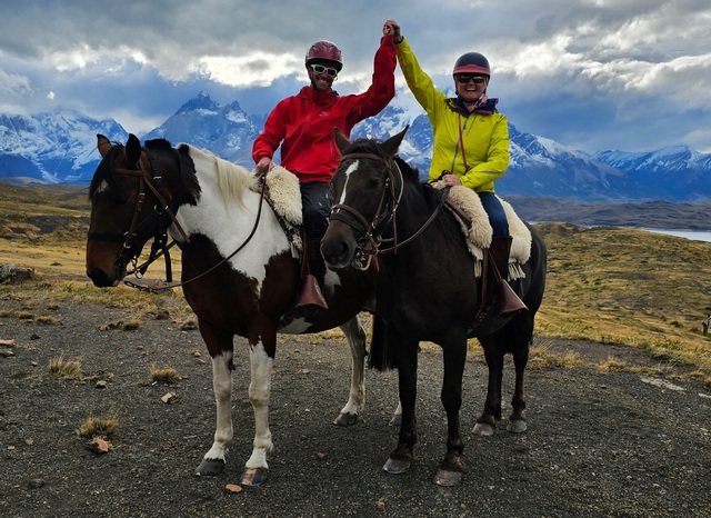 A couple holds hands while posing while riding horses at Estancia Cristina, a luxury estancia located in the heart of Los Glaciares National Park in the Patagonia region of Argentina