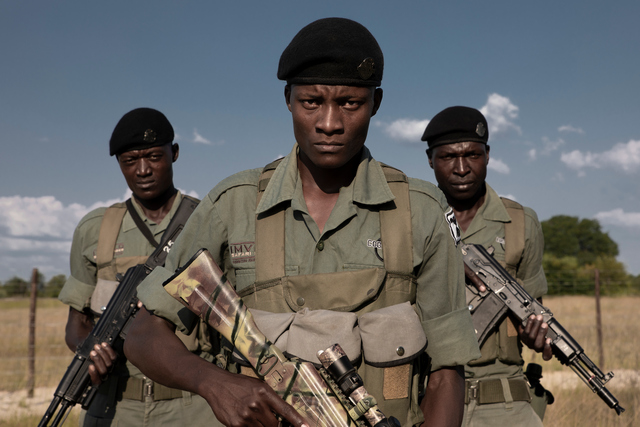 Three armed anti-poaching rangers pose with their weapons in Hwange National Park