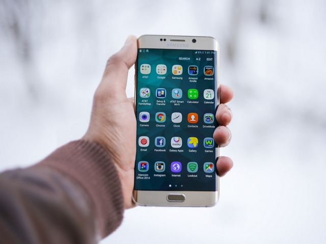 hand holding a smart phone with app screen visible