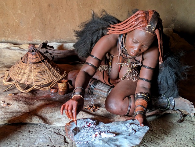 A Himba woman preparing something over a fire on a luxury safari in Namibia