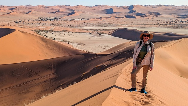 A woman takes a break while hiking Big Daddy Dune at Sossusvlei, Namibia during a luxury safari outing from Camp Sossus