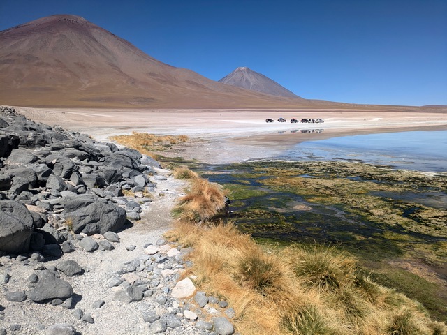 A few vehicles dwarfed by the looming Volcan Licancabur in Bolivia