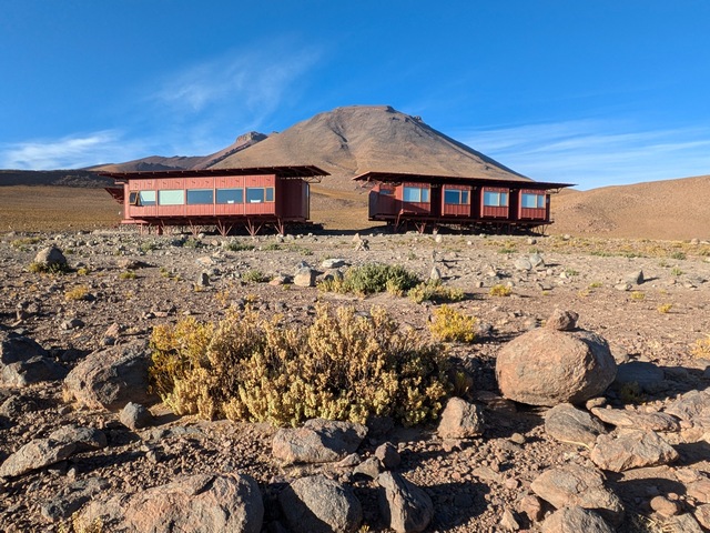 Explora's Ramaditas Lodge consists of wo small red buildings in front of a high-altitude volcano