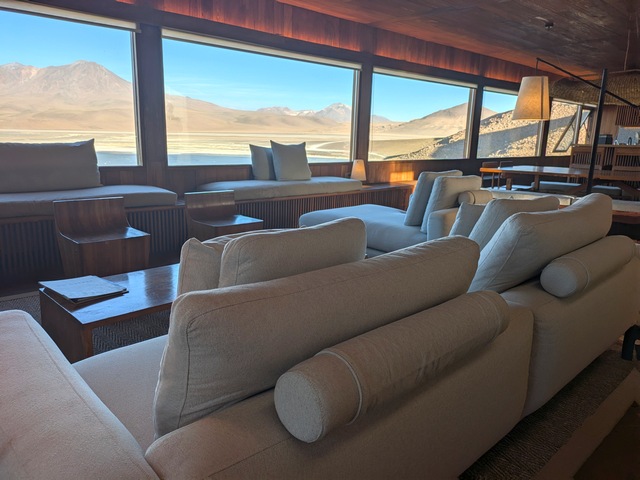 Common room at Explora Ramaditas lodge, with several white couches facing huge picture windows
