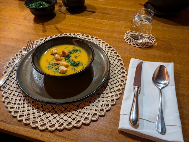 A ceramic bowl on a dining room table at Explora Ramaditas Lodge with a golden yellow soup