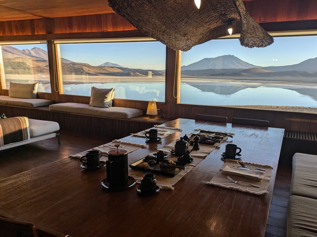 Wooden dining table looking out over an expansive lake with beautiful volcanos at Explora Ramaditas Lodge