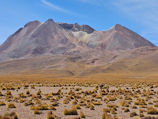 High altitude steppe leading to a huge volcano with a large crater in Bolivia