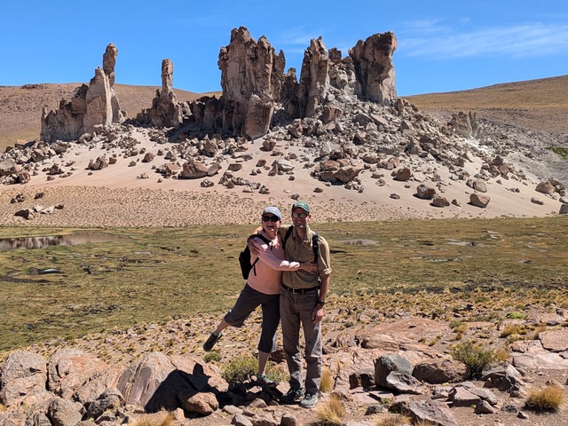 Two hikers pose in front of a rocky yardang encountered on Explora's Travesia