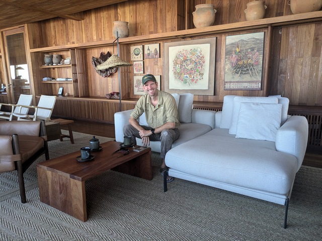 A man sitting on a couch next to local artwork inside Explora Chituca Lodge on the Travesia