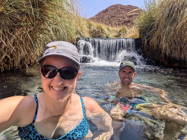 Two people smiling in a private hot springs pool at Puritama Hot Springs in the Atacama