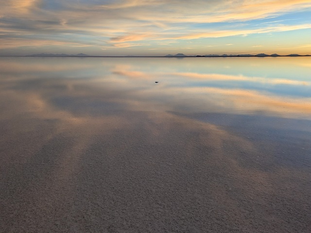 clouds reflecting on the mirror-like uyuni salt flats at sunset