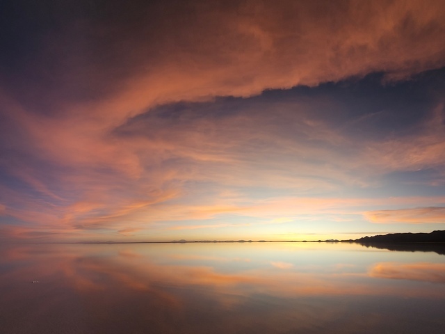 thick red clouds reflecting in the pink and blue waters below on the uyuni salt flats near colchani