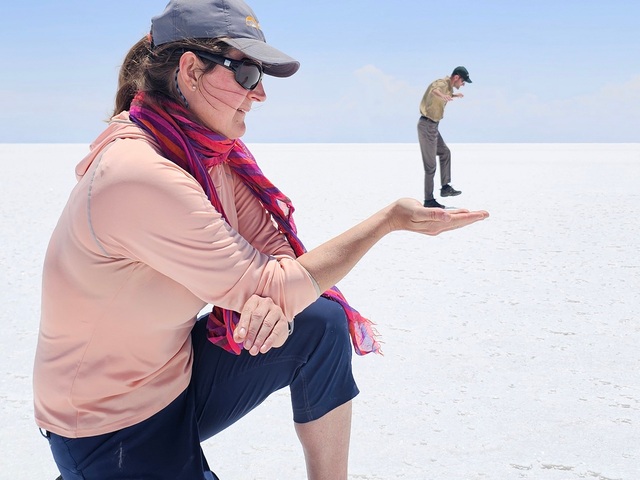 perspective photo on the uyuni salt flats of a giant woman holding a man in her hand