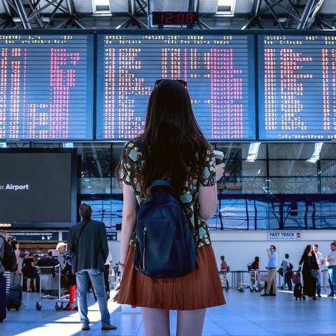traveler at an airport looking at the arrivals screen