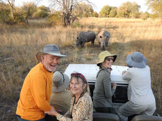 Guests on a luxury safari in Hwange National Park are all smiles as they view the recently reintroduced white rhinos from a safari vehicle