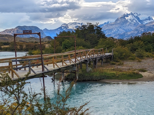 A wooden bridge crosses the turquoise waters of the Rio Caterina at Estancia Cristina