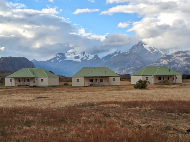 three yellow cabins with green roofs on the steppe of Estancia Cristina
