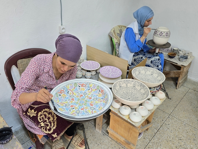 two women painting white pottery by hand at a women's artisan cooperative in Fes