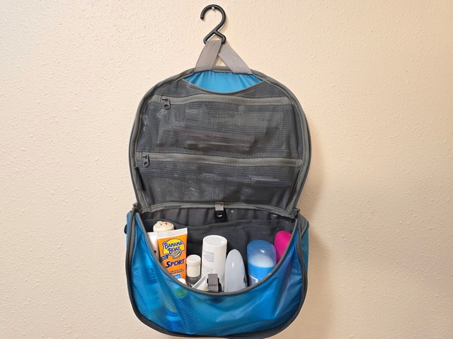a hanging toiletry bag opened up, showing toiletries neatly packed inside