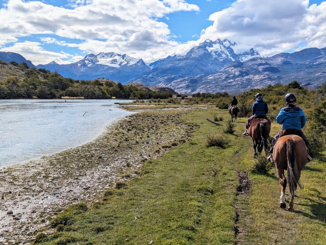 Three horseback riders along the shores of Rio Caterina at Estancia Cristina