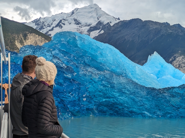 two tourists overlooking stunning icebergs and glaciated peaks from a catamaran on lago argentina in patagonia