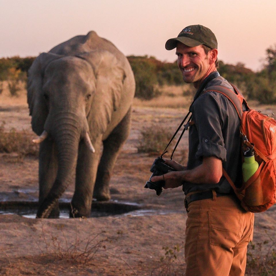 Moraway Adventures CEO Chris Moriarty looking back at the camera while standing near an elephant he was photographing in Hwange National Park Zimbabwe