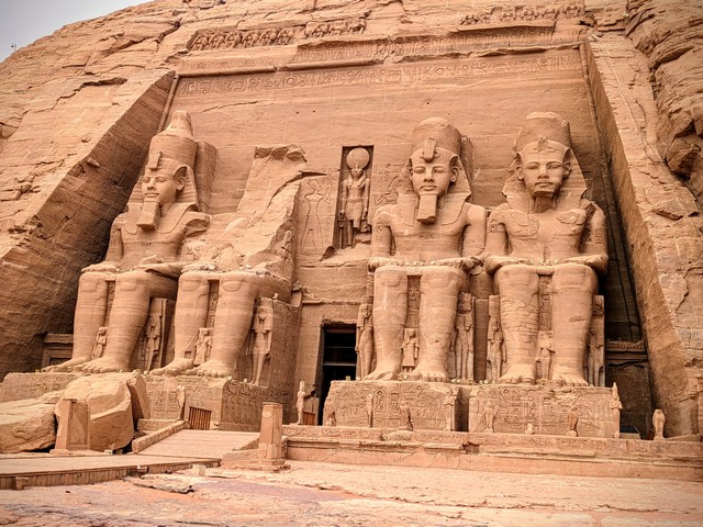 Entrance to the Great Temple of Abu Simbel in Egypt, featuring four colossal statues of Pharaoh Ramesses II carved into the sandstone cliff surrounding the temple doorway.