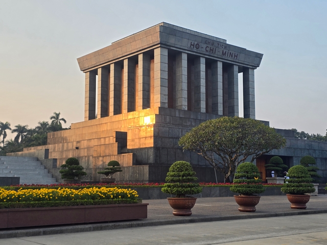 Ho Chi Minh Mausoleum in Hanoi, Vietnam at sunset, with warm golden sunlight reflecting off the granite façade of the historic monument.