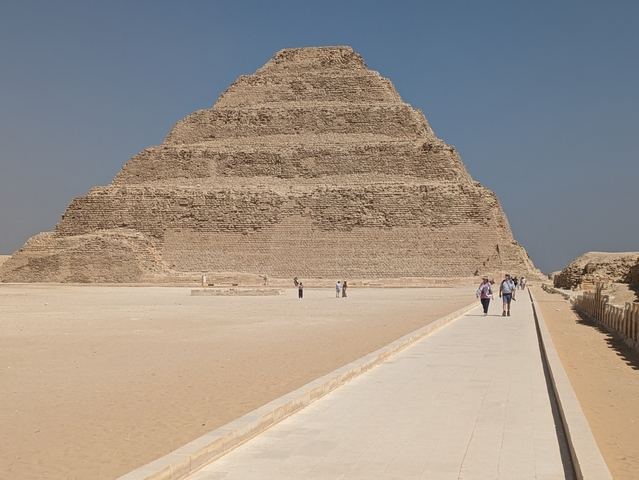 Tourists walking in front of the Step Pyramid of Djoser at Saqqara, Egypt.