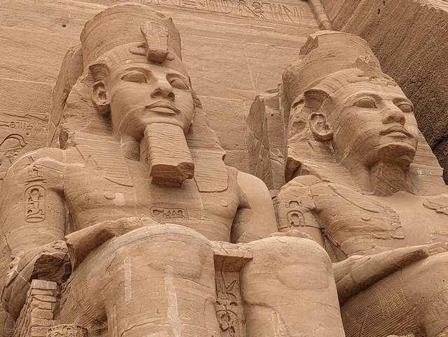 Close-up of two giant stone statues of Ramesses II that guard the entrance to the Great Temple at Abu Simbel.