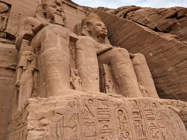 Looking up from below at two of the giant statues of Ramesses II carved into the stone at the Great Temple of Abu Simbel in Egypt.