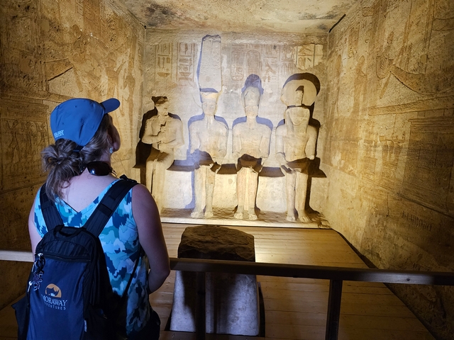 A visitor looking at the four stone statues of the gods inside the inner sanctuary of the Great Temple at Abu Simbel, Egypt.
