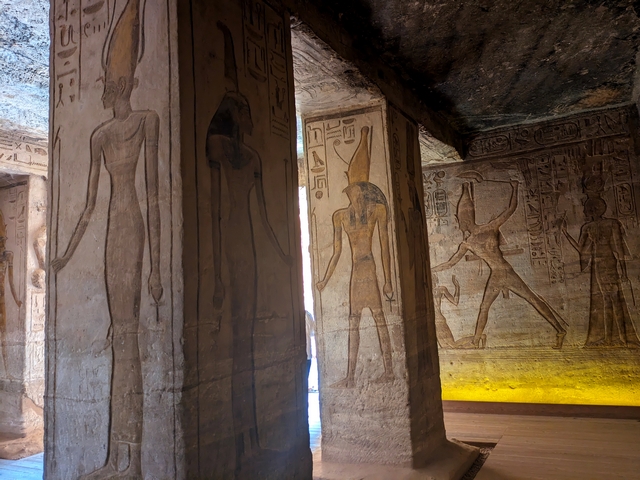 Artwork etched into stone on the columns and walls inside the Small Temple of Hathor at Abu Simbel, with portraits of various gods and an image of Ramesses II smiting an enemy as Queen Nefertari looks on.