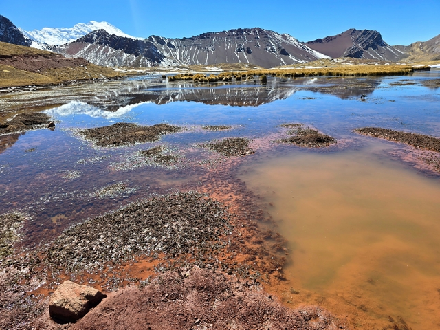 Mountains reflect in still blue waters of the high-altitude wetlands near Peru's Ausangate mountain.