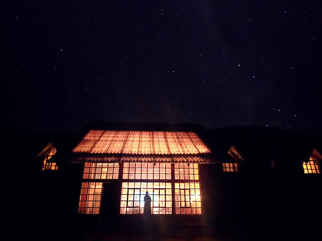 Huampococha Lodge illuminated at night, against a backdrop of a clear, dark, starry night sky.