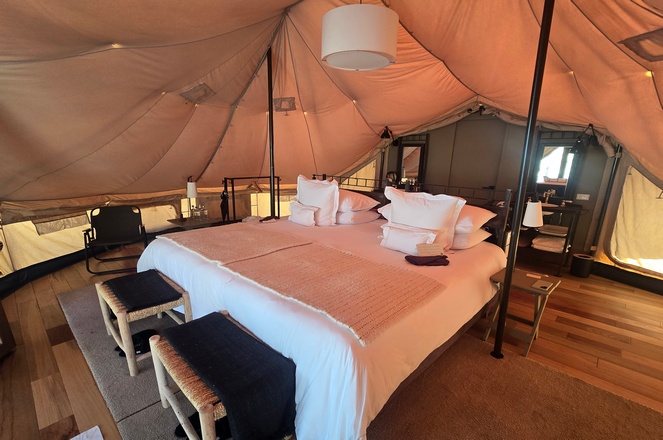 An inviting queen-sized bed perfectly set and waiting for visitors inside a canvas safari-style tent at Tinajani by Andean in Peru.