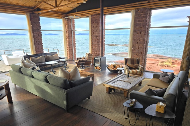 Comfortable sitting room at Titilaka Lodge, with huge picture windows showing the expansive lake behind an elegantly furnished sitting area.